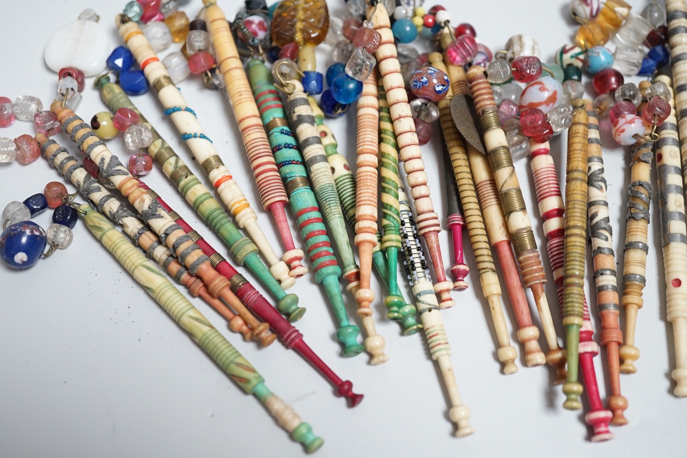 Twenty one 19th century stained and turned bone lace bobbins with glass bead tops and thirteen ornate bone and metal decorated lace bobbins with bead tops (35)